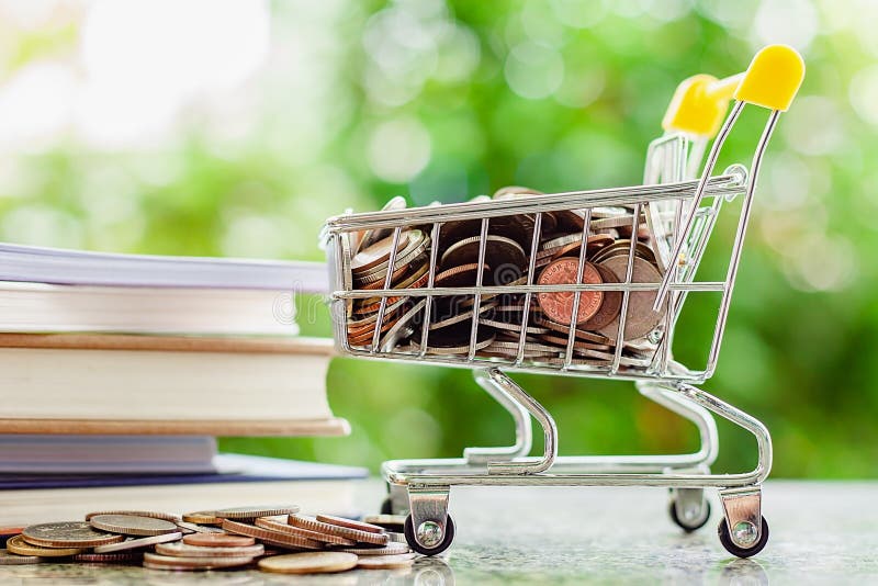 Por completo de la moneda del dinero en mini carro de la compra o carretilla con la pila o imágenes de archivo libres de regalías Por completo de la moneda del dinero en mini carro de la compra o carretilla con la pila o imágenes de archivo libres de regalías