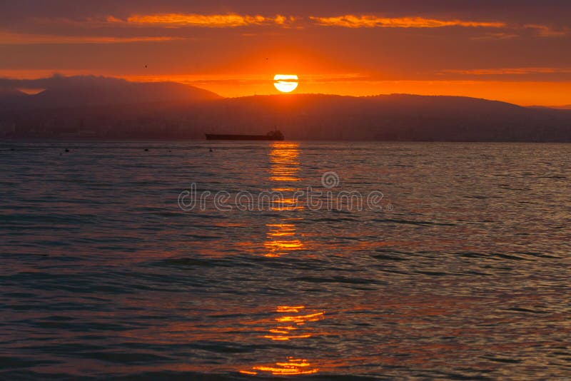Por do sol bonito entre as nuvens Os raios do sol são simplesmente bonitos Cidade, montanhas e navios no mar fotos de stock royalty free Por do sol bonito entre as nuvens Os raios do sol são simplesmente bonitos Cidade, montanhas e navios no mar fotos de stock royalty free
