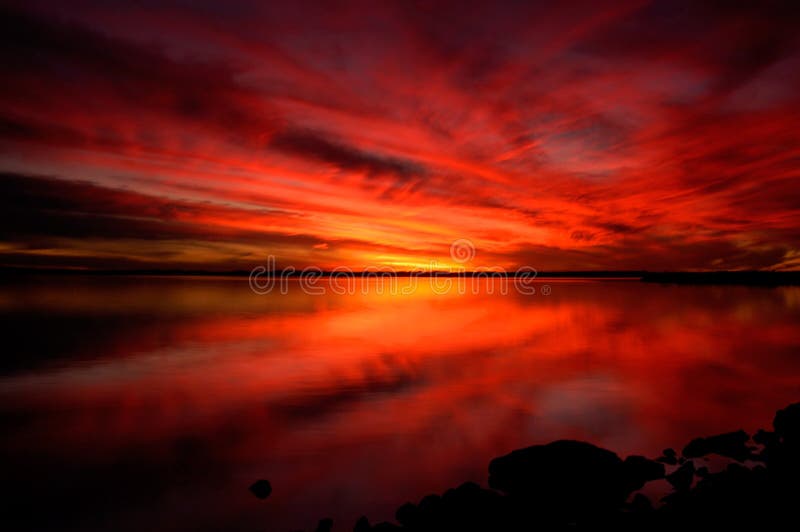 A fiery red sunset reflected in a lake. A fiery red sunset reflected in a lake.