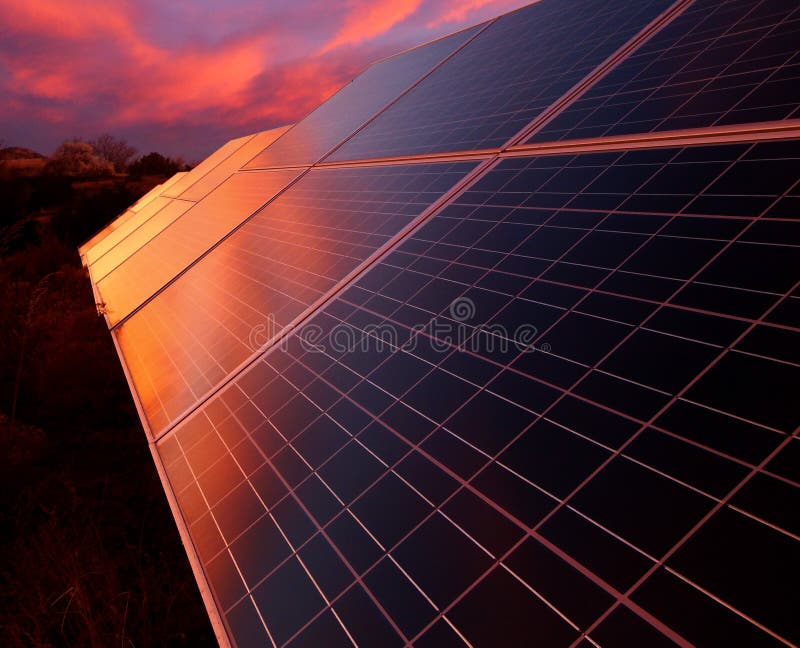 A glowing sunset is reflected in the panels of solar array composed of photovoltaic panels. Located in New Mexico. A glowing sunset is reflected in the panels of solar array composed of photovoltaic panels. Located in New Mexico.