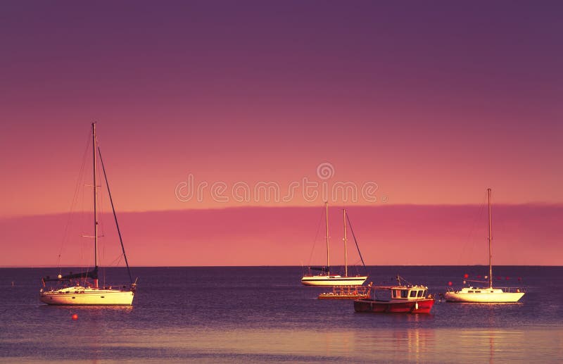 Por do sol vermelho sobre o mar azul, o céu roxo e os iate no parque de estacionamento Paisagem cênico do mar do verão na noite b imagem de stock Por do sol vermelho sobre o mar azul, o céu roxo e os iate no parque de estacionamento Paisagem cênico do mar do verão na noite b imagem de stock
