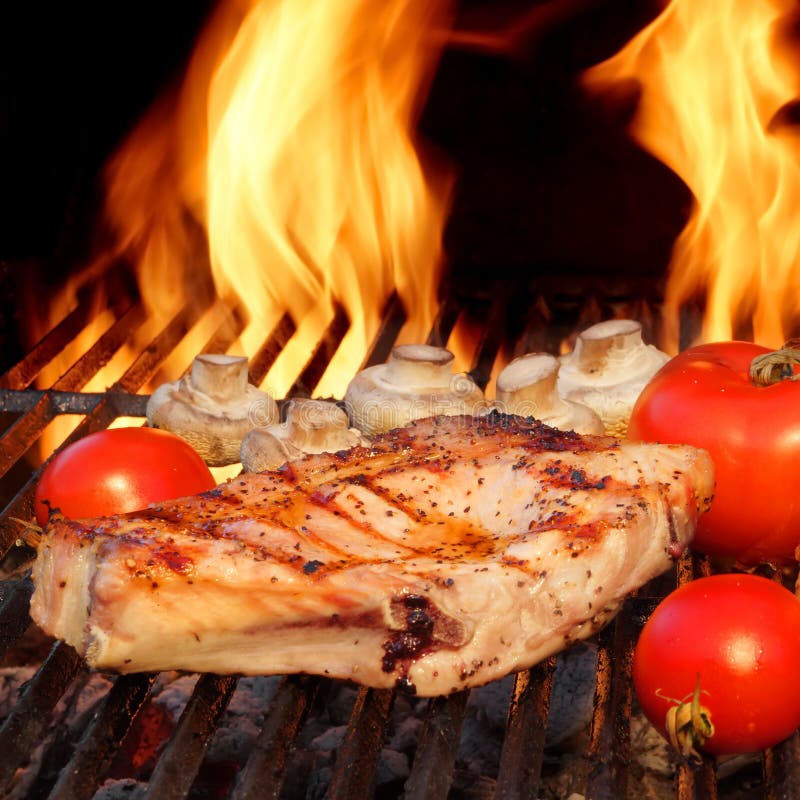 Porc Rib Steaks, tomate et champignons sur le gril chaud de BBQ photographie stock libre de droits Porc Rib Steaks, tomate et champignons sur le gril chaud de BBQ photographie stock libre de droits