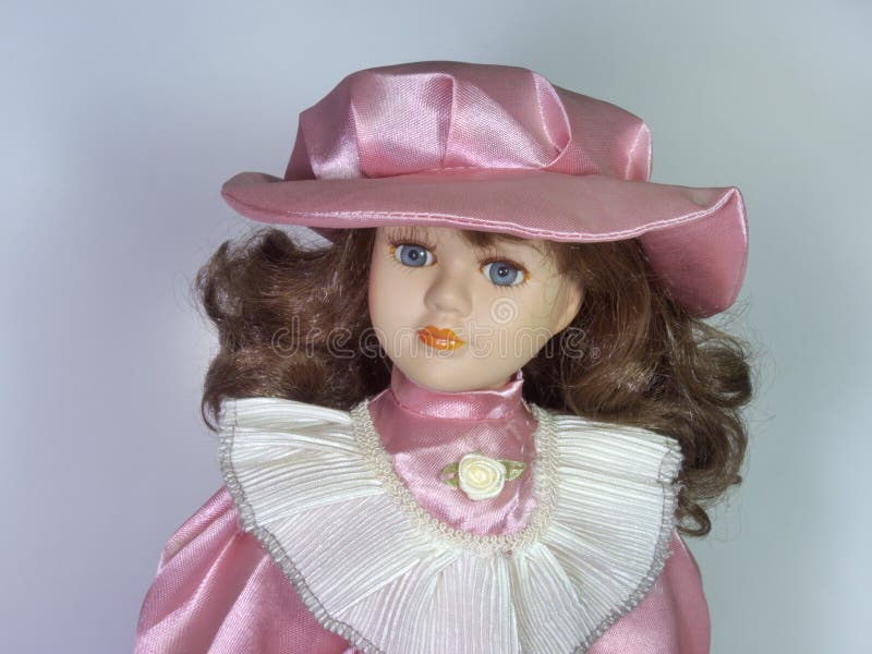 A porcelain doll with big beautiful eyes. In an elegant hat with