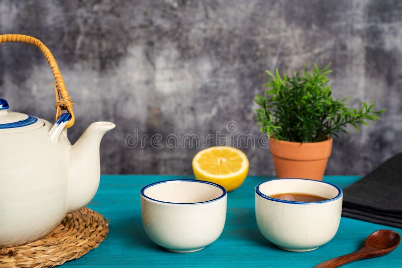 https://thumbs.dreamstime.com/b/porcelain-teapot-next-to-two-cups-one-tea-wooden-teaspoon-half-lemon-blue-table-close-up-270436263.jpg