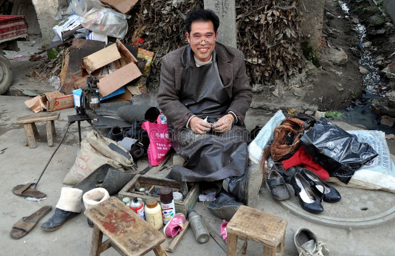 A cobbler with his outdoor shop set up along the edge of a street doing shoe repairs in the Sichuan village of Wan Jia, China. A cobbler with his outdoor shop set up along the edge of a street doing shoe repairs in the Sichuan village of Wan Jia, China.