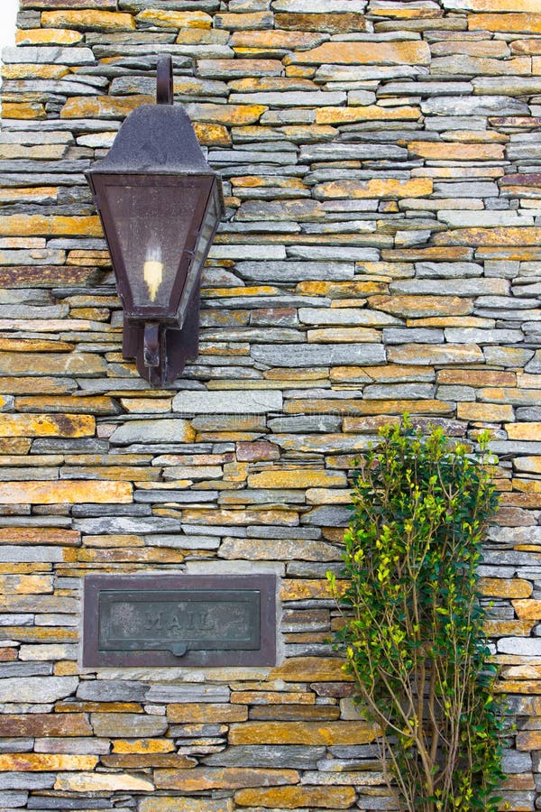 Details on the facade of a pretty stone house; porch light, mail slot and plant. Details on the facade of a pretty stone house; porch light, mail slot and plant