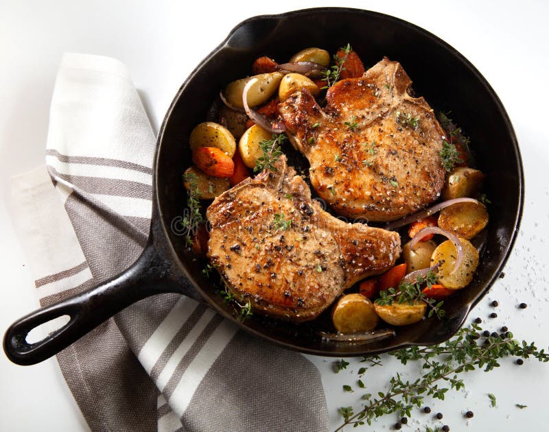 Pork chops in cast iron skillet with vegetables