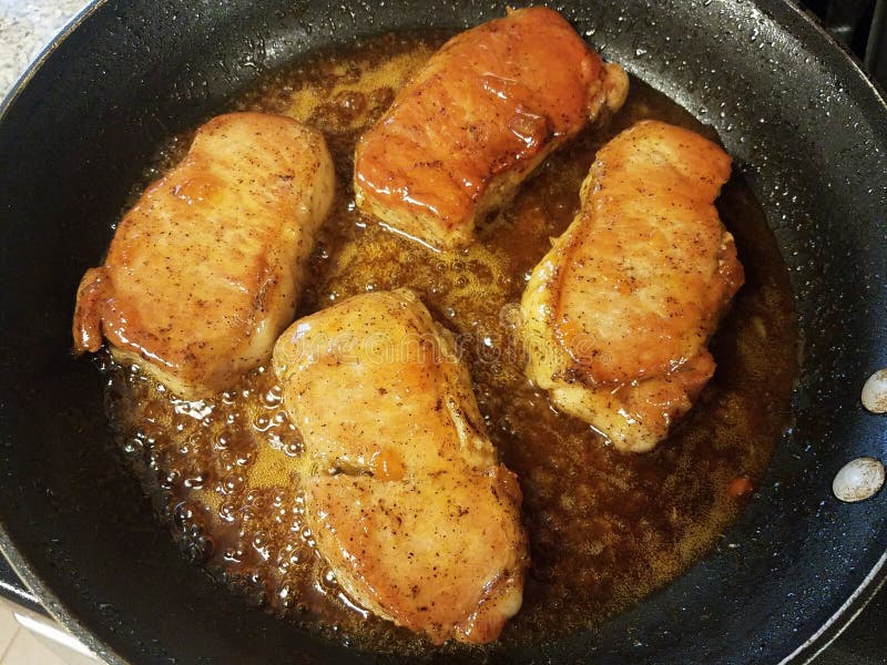 Pork chops cooking in skillet or frying pan