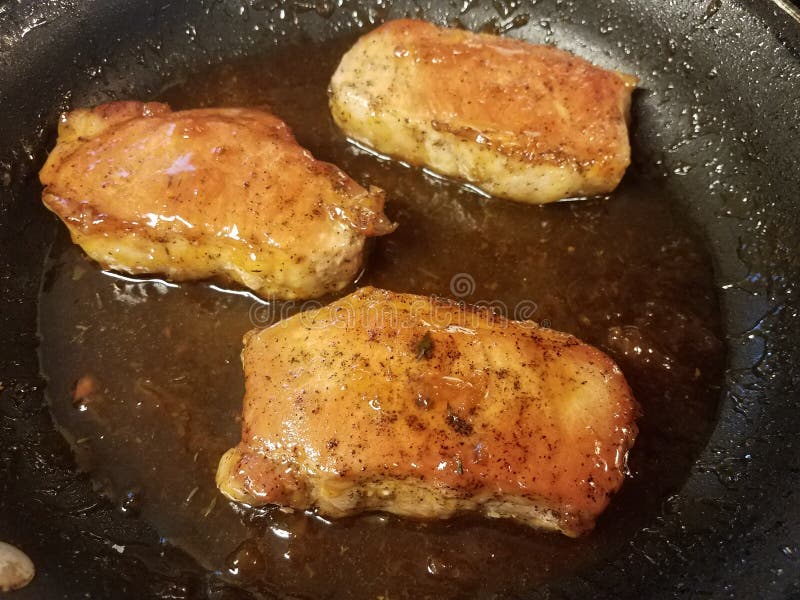 Pork chops cooking in skillet or frying pan