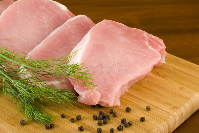Pork chops with fresh dill on a cutting board