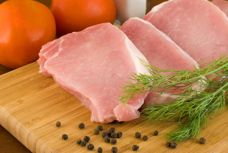 Pork chops with fresh dill on a cutting board