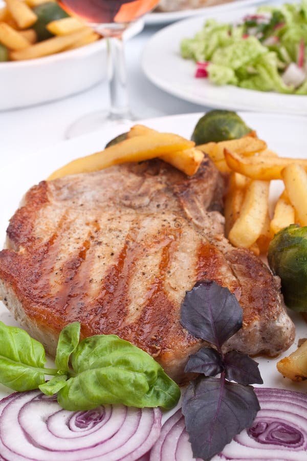 Pork chops with fries and brussels sprouts stock photo