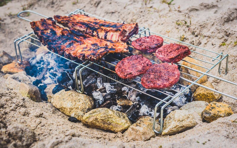 Pork ribs and burgers on homemade improvised BBQ barbecue grill.