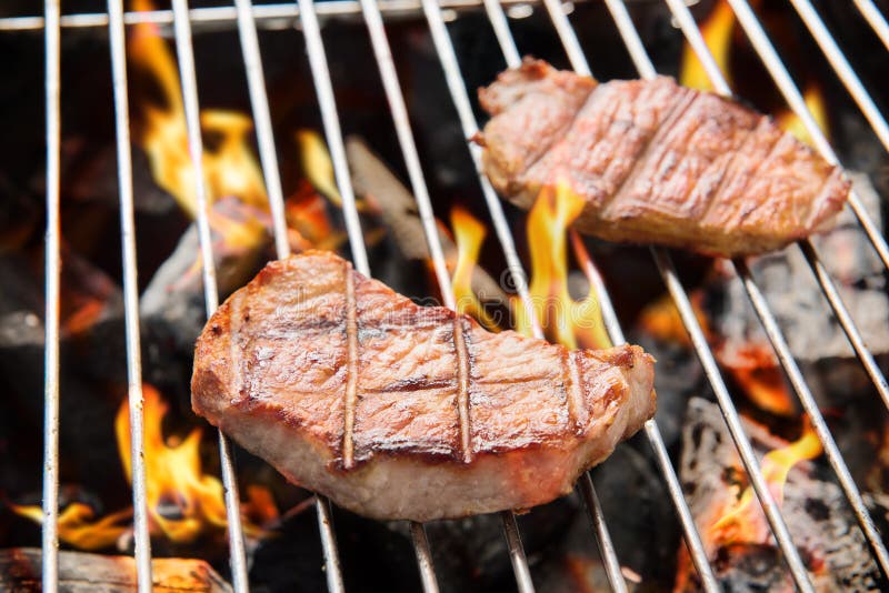 Pork steak cooking over flaming grill. royalty free stock photo Pork steak cooking over flaming grill. royalty free stock photo