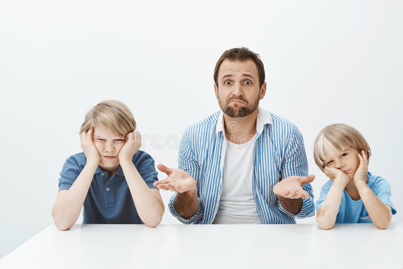 Porqué los hijos están enojados Retrato del suegro nervioso desorientado que se sienta con dos muchachos lindos en la tabla, enco