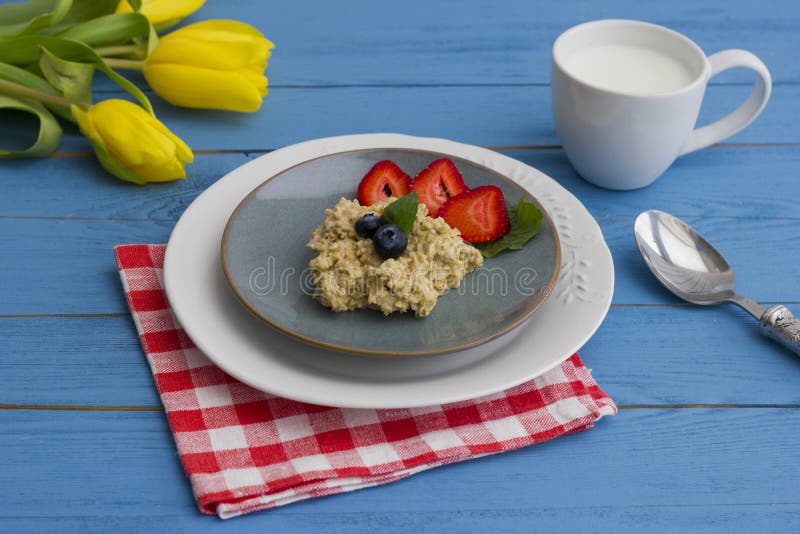Porridge con le bacche, le fragole fresche ed i mirtilli Una tazza di latte fotografie stock libere da diritti Porridge con le bacche, le fragole fresche ed i mirtilli Una tazza di latte fotografie stock libere da diritti
