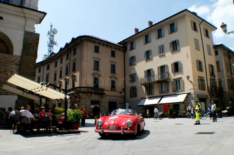 A red Porsche 356 Speedster passing through Tasso street Bergamo, Italy before the crowd during the 2016 Mille Miglia classic car race. Held 254 times between 1927 and 1957 as a sportscar road race, it has been organized again since 1977 as a regularity race for classic cars on the path of the original race. The 2015 edition has been the first one to pass through Bergamo where the photo has been taken. A red Porsche 356 Speedster passing through Tasso street Bergamo, Italy before the crowd during the 2016 Mille Miglia classic car race. Held 254 times between 1927 and 1957 as a sportscar road race, it has been organized again since 1977 as a regularity race for classic cars on the path of the original race. The 2015 edition has been the first one to pass through Bergamo where the photo has been taken