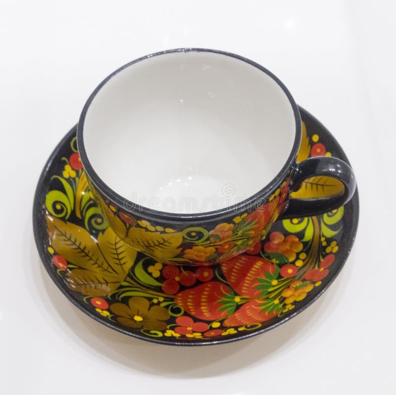 Porseleinkop en schotel van een theestel in Russische stijl in Khokhloma wordt behandeld die stock foto Porseleinkop en schotel van een theestel in Russische stijl in Khokhloma wordt behandeld die stock foto