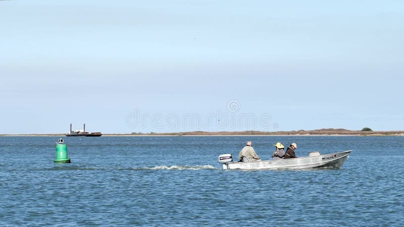 Port aransas tx 7 luty 2020 : łódź rybacka z silnikiem i trzema osobami, gdy wjeżdżają na pokład w słoneczny dzień