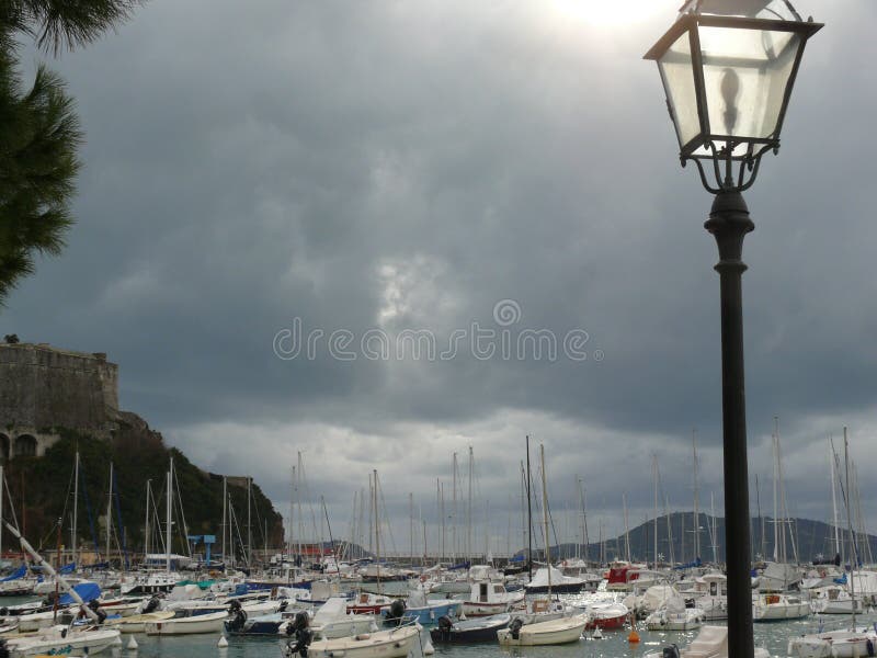 Port de Lerici avec bateaux amarrés Ciel nuageux Le soleil illumine une lampe de rue images stock