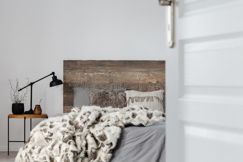 Porta aperta a una camera da letto grigia ed elegante con design rustico, spazio su muro vuoto fotografie stock