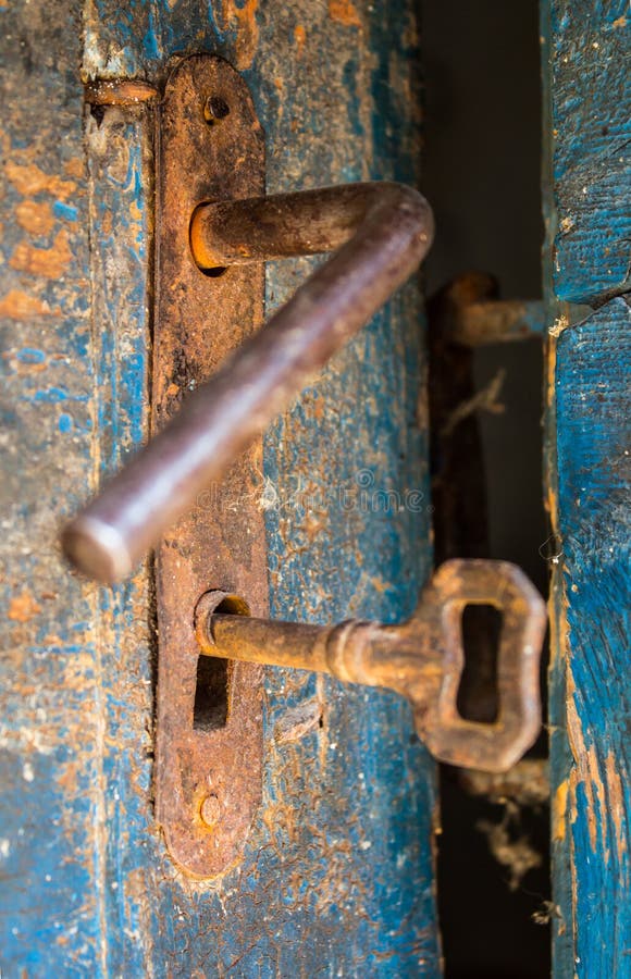 Porta rústica velha aberta com fechamento oxidado, chave e buraco da fechadura