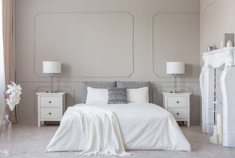 Portale di legno bianco del camino nell'interno luminoso della camera da letto, spazio della copia sulla parete grigia vuota fotografia stock libera da diritti