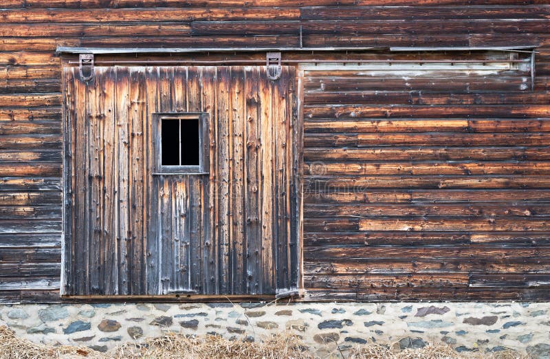 Side of Barn showing Distressed Board Door with Window and Stone Wall Foundation. Side of Barn showing Distressed Board Door with Window and Stone Wall Foundation.