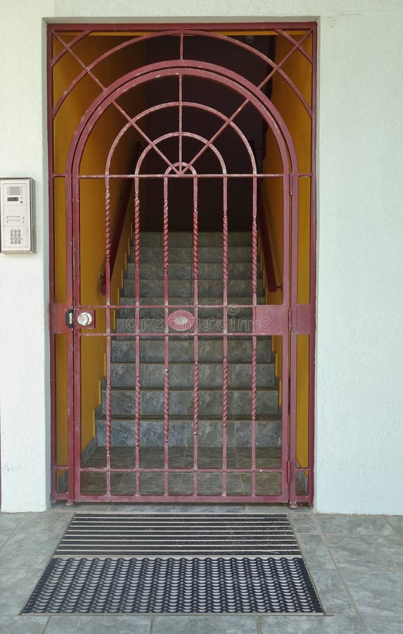 A detailed wrought iron gate secures the entrance to this apartment. Tiled steps disappear into the background. A detailed wrought iron gate secures the entrance to this apartment. Tiled steps disappear into the background.