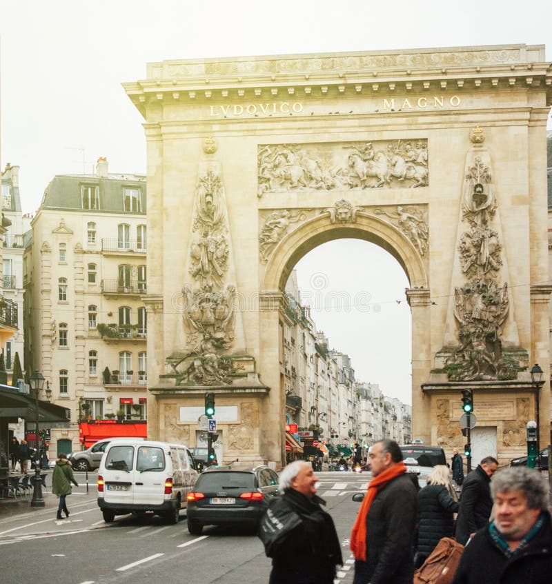PARIS, FRANCE - JAN 23, 2013: Porte Saint-Denis triumphal arch with the entablature bronze inscription LUDOVICO MAGNO, `To Louis the Great` on a sunny PArisian day. PARIS, FRANCE - JAN 23, 2013: Porte Saint-Denis triumphal arch with the entablature bronze inscription LUDOVICO MAGNO, `To Louis the Great` on a sunny PArisian day