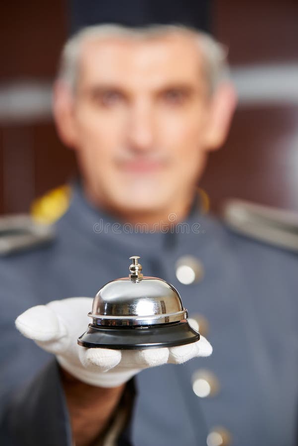 Portero que sostiene la campana del hotel a mano fotografía de archivo Portero que sostiene la campana del hotel a mano fotografía de archivo