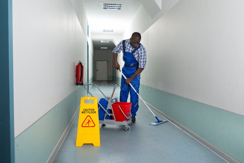 Portrait Of Young African Male Janitor Cleaning Floor In Corridor. Portrait Of Young African Male Janitor Cleaning Floor In Corridor