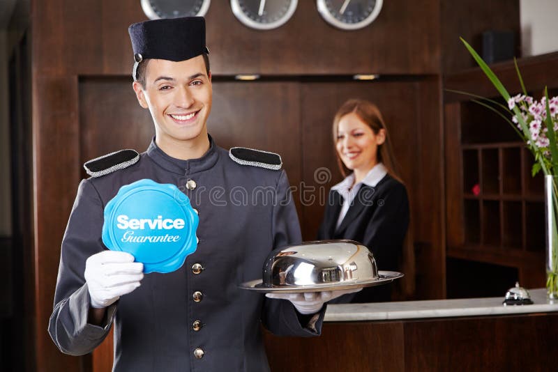 Smiling concierge in hotel reception holding service sign. Smiling concierge in hotel reception holding service sign