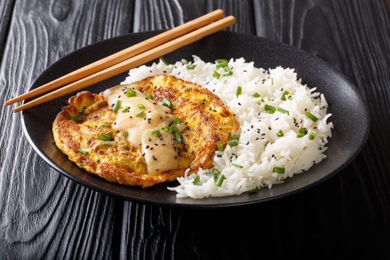 Portion of fried Chinese omelet Egg Foo Young served with a side dish of white rice close-up on a plate. Horizontal