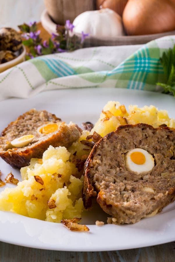 Portion of meatloaf on white plate with mashed potatoes