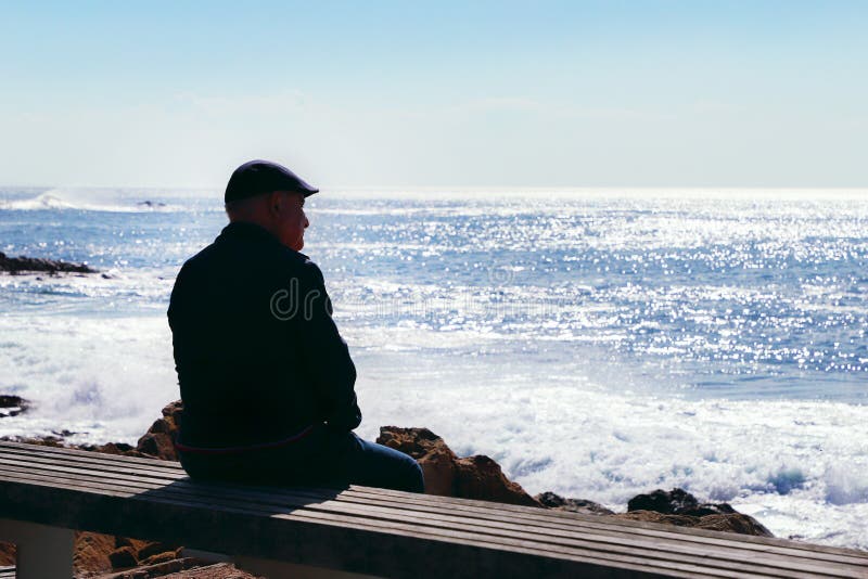 Old man sit on bench by the Atlantic ocean view