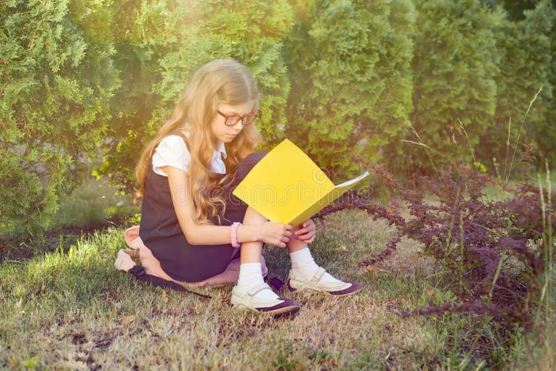 Portr?t im Freien des Schulm?dchens sitzend auf dem Grasleseschulnotizbuch Beginnen Sie die Schule lizenzfreies stockbild Portr?t im Freien des Schulm?dchens sitzend auf dem Grasleseschulnotizbuch Beginnen Sie die Schule lizenzfreies stockbild
