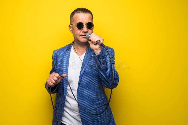 Portrai dell'uomo maturo di medio evo in vestito che canta sopra il microfono isolato su fondo giallo Concetto di Cantante fotografie stock Portrai dell'uomo maturo di medio evo in vestito che canta sopra il microfono isolato su fondo giallo Concetto di Cantante fotografie stock
