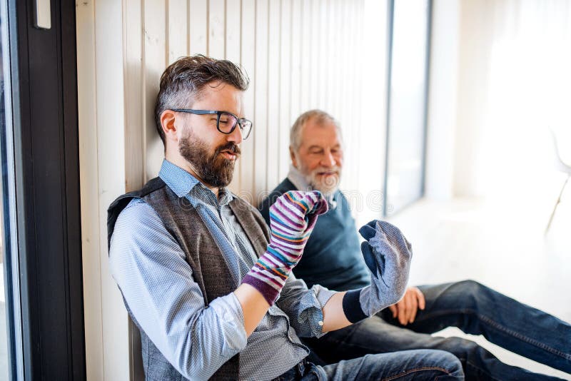 Portrait of adult hipster son and senior father sitting on floor indoors at home, having fun. royalty free stock images Portrait of adult hipster son and senior father sitting on floor indoors at home, having fun. royalty free stock images