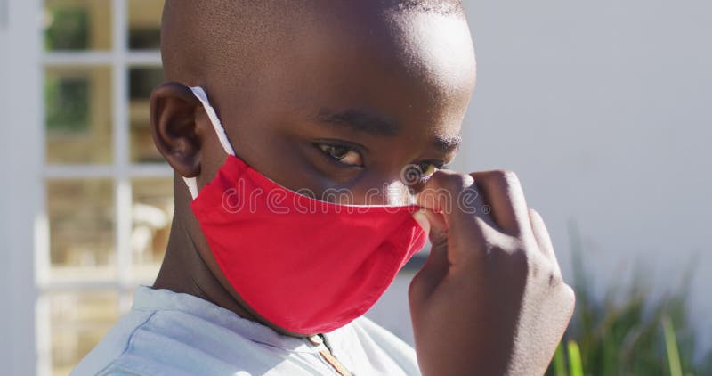 Portrait of african american boy wearing face mask outdoors on a bright sunny day