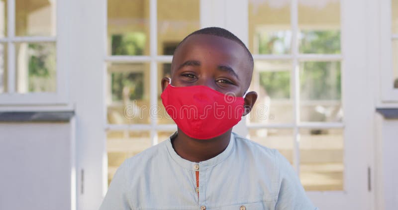 Portrait of african american boy wearing face mask outdoors on a bright sunny day