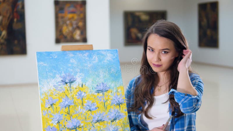 Portrait. Artist smiling standing near a picture of flowers.