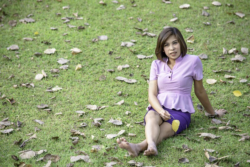Portrait Asean woman sitting on the lawn in a park stock photos Portrait Asean woman sitting on the lawn in a park stock photos