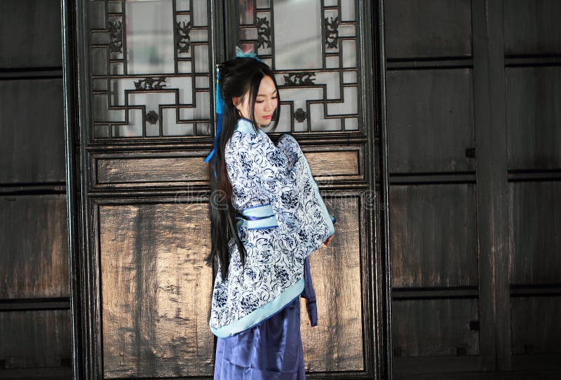 Portrait of Asian Chinese girl in traditional dress, wear blue and white porcelain style Hanfu, stand by a door