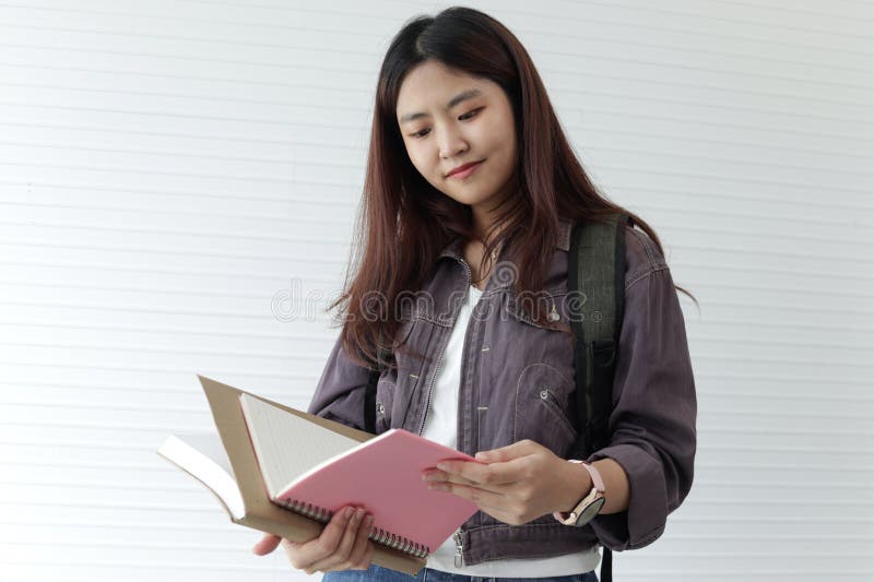 Portrait of Asian high school girl student holding book, standing in classes. Female student engages in study. Happy college pupil stock photo
