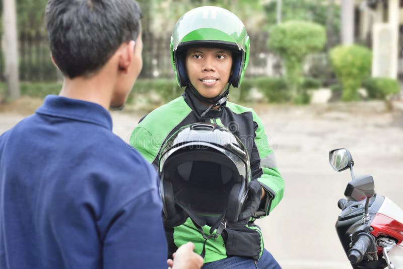 Portrait of asian motorcycle taxi driver giving the helmet