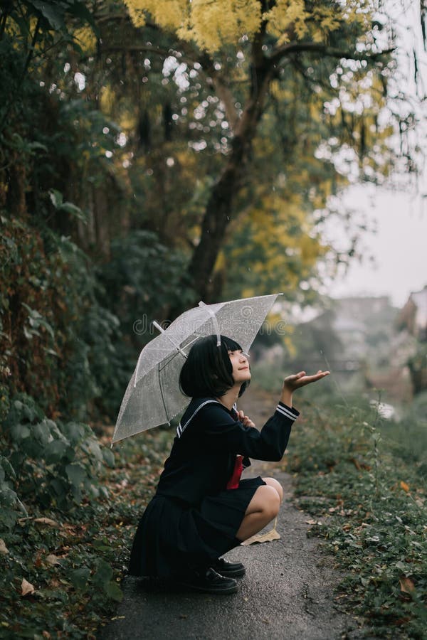 Portrait of Asian school girl walking with umbrella at nature walkway stock images Portrait of Asian school girl walking with umbrella at nature walkway stock images