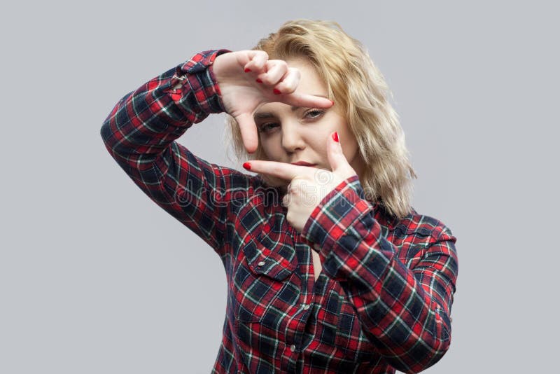 Portrait of attentive beautiful blonde young woman in casual red checkered shirt standing with cropping composition gesture stock photo Portrait of attentive beautiful blonde young woman in casual red checkered shirt standing with cropping composition gesture stock photo