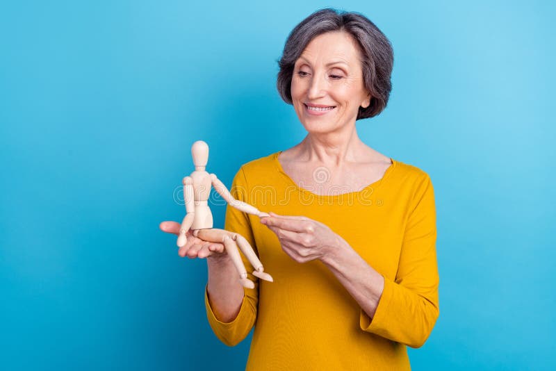 Portrait of attractive cheerful woman holding in hands wooden doll playing game isolated over bright blue color