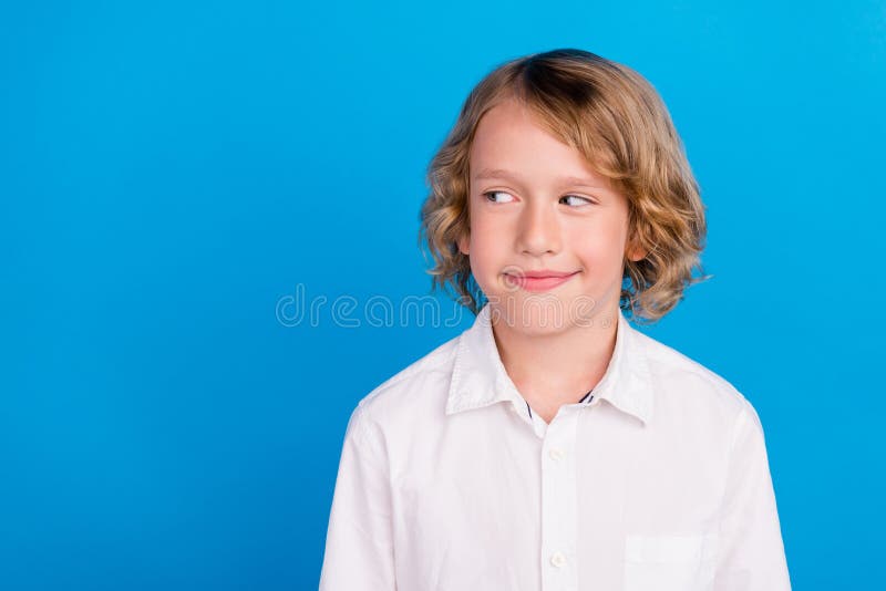 Portrait of attractive curious cheerful boy looking aside copy empty space  over vibrant blue color background